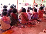 The ladies, finished with preparing the flower decorations, sit sarong-clad, krama-wrapped, and feet propped - Takeo